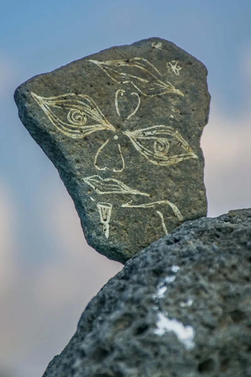 Flat stone etched with a simple face and spiral lines